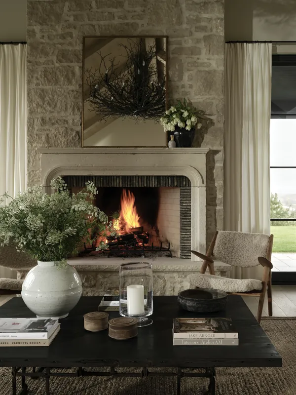 Farmhouse living room with a limestone fireplace surround and a natural stone wall