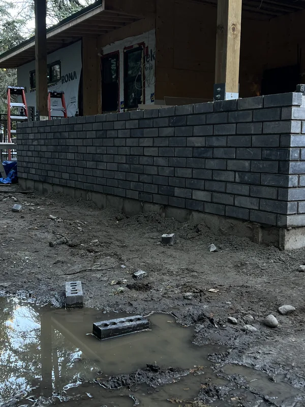 Dark brick being laid around the base of a new addition on a Whitby home