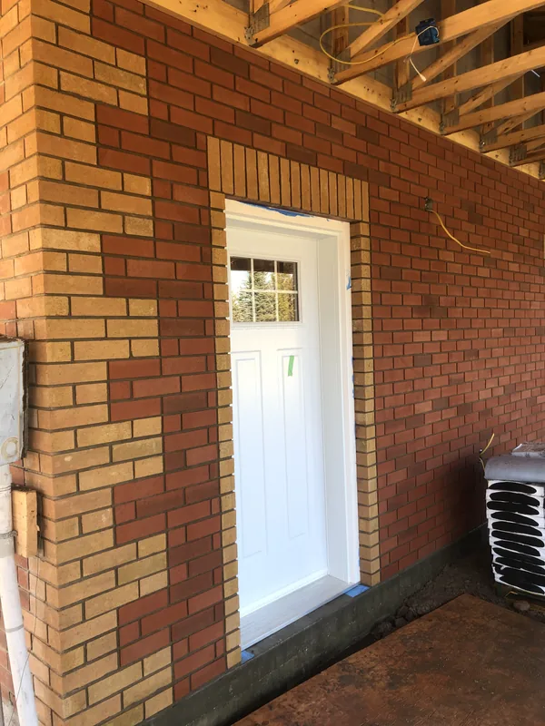 Brick door surround with buff brick detailing on a Strongback job in nearby Clarington