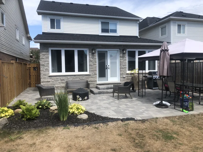Finished paver back patio with seating and planting beds at a Whitby home