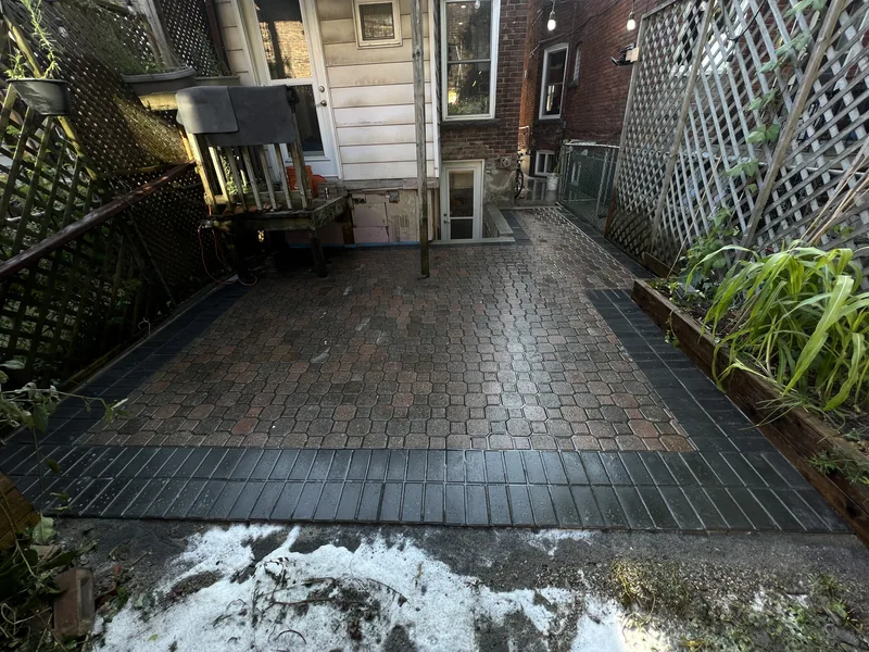 Rear paver patio with a dark border behind a Toronto home