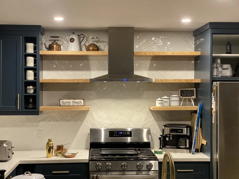 Kitchen with navy cabinets, floating wood shelves and a tiled backsplash