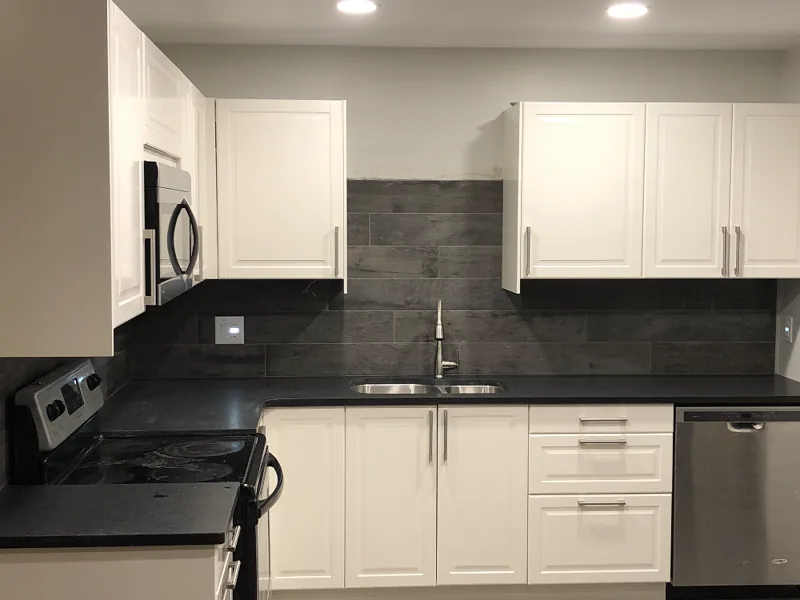 Kitchen with white shaker cabinets and a dark tile backsplash