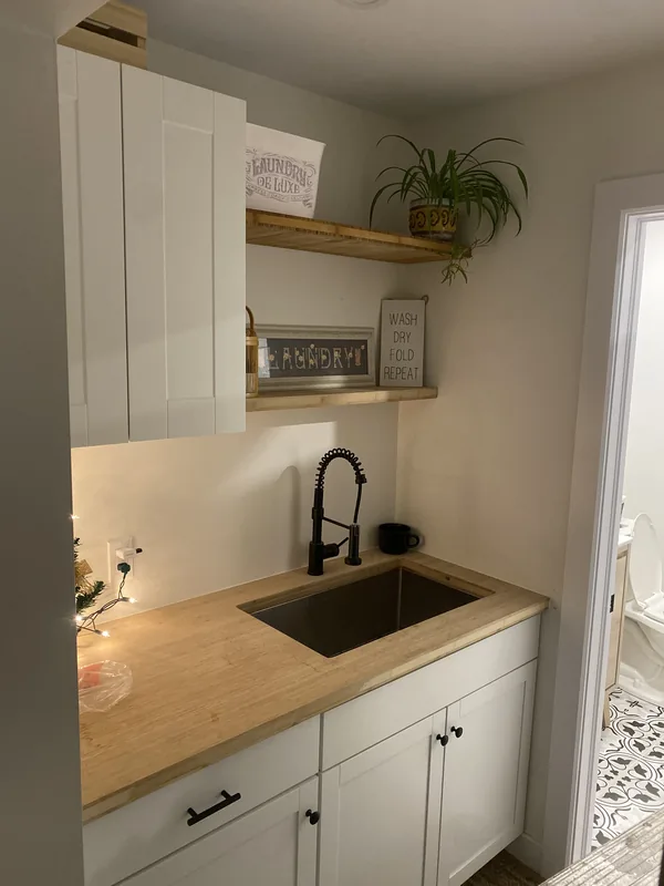 Kitchenette with white shaker cabinets, butcher block counter and floating shelves