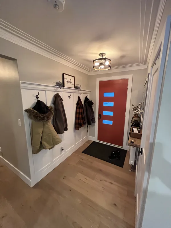 Mudroom with built-in bench, hooks and white panelling