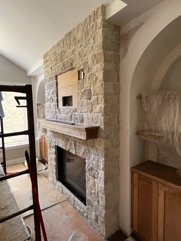 Floor to ceiling natural stone fireplace surround with a timber mantel in Courtice