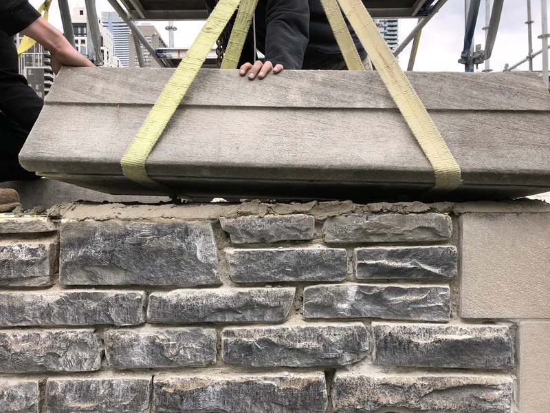 Precast coping being lowered onto a new stone wall in Toronto