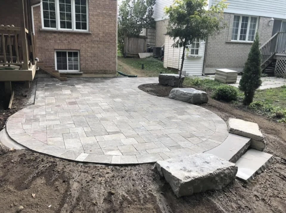 Curved paver patio with armour stone steps in a rear yard