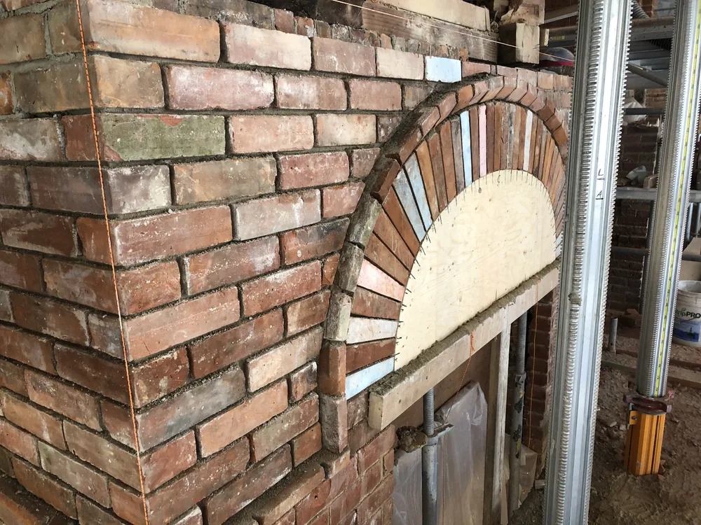 Brick arch being rebuilt with reclaimed brick in an old masonry wall